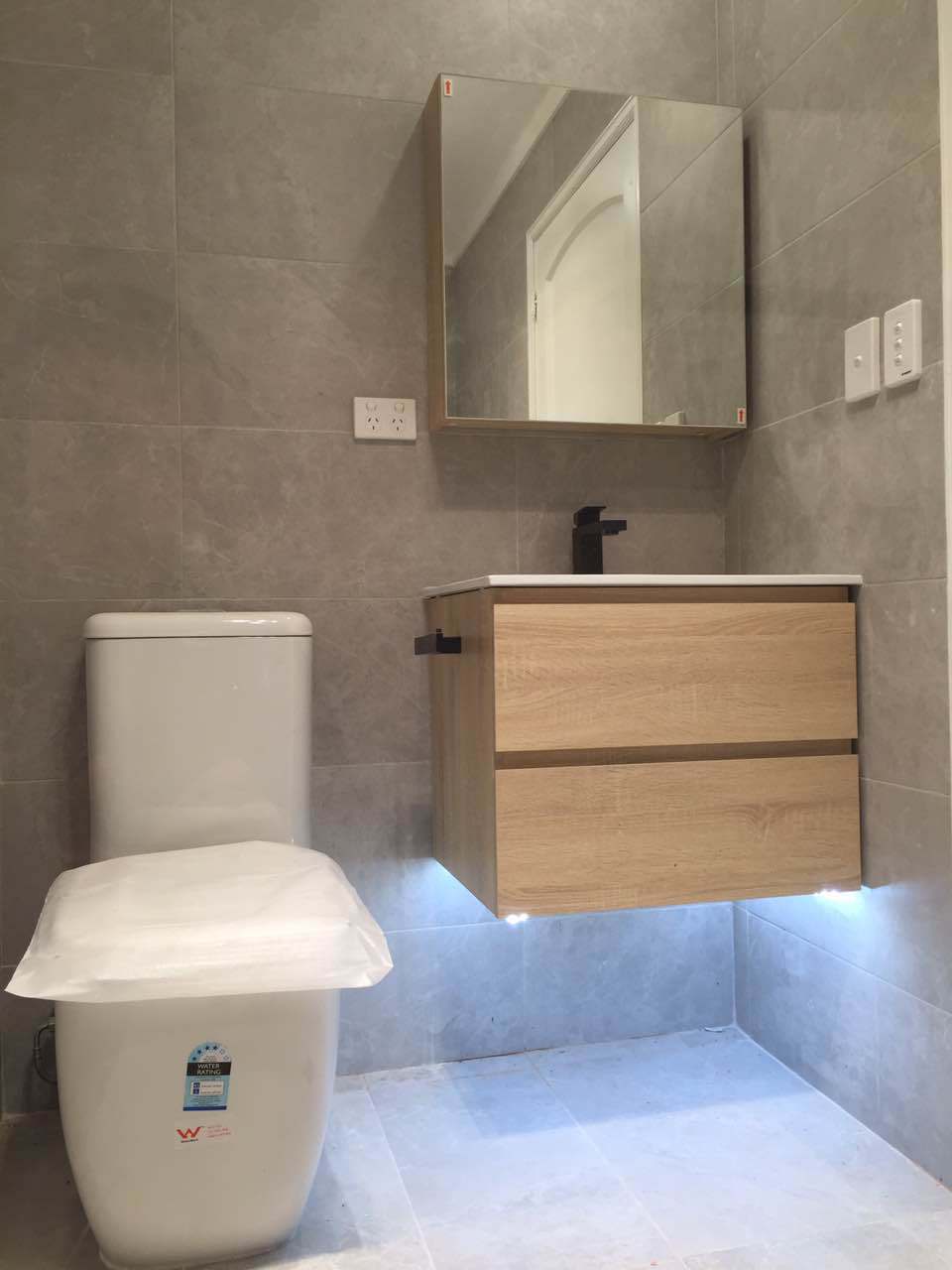 Timber vanity with integrated lighting and grey wall tiles