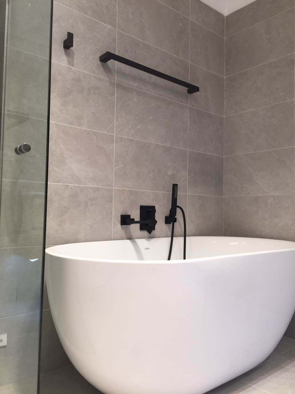 Freestanding bath with grey wall tiling and black fittings from the original AMAB project gallery
