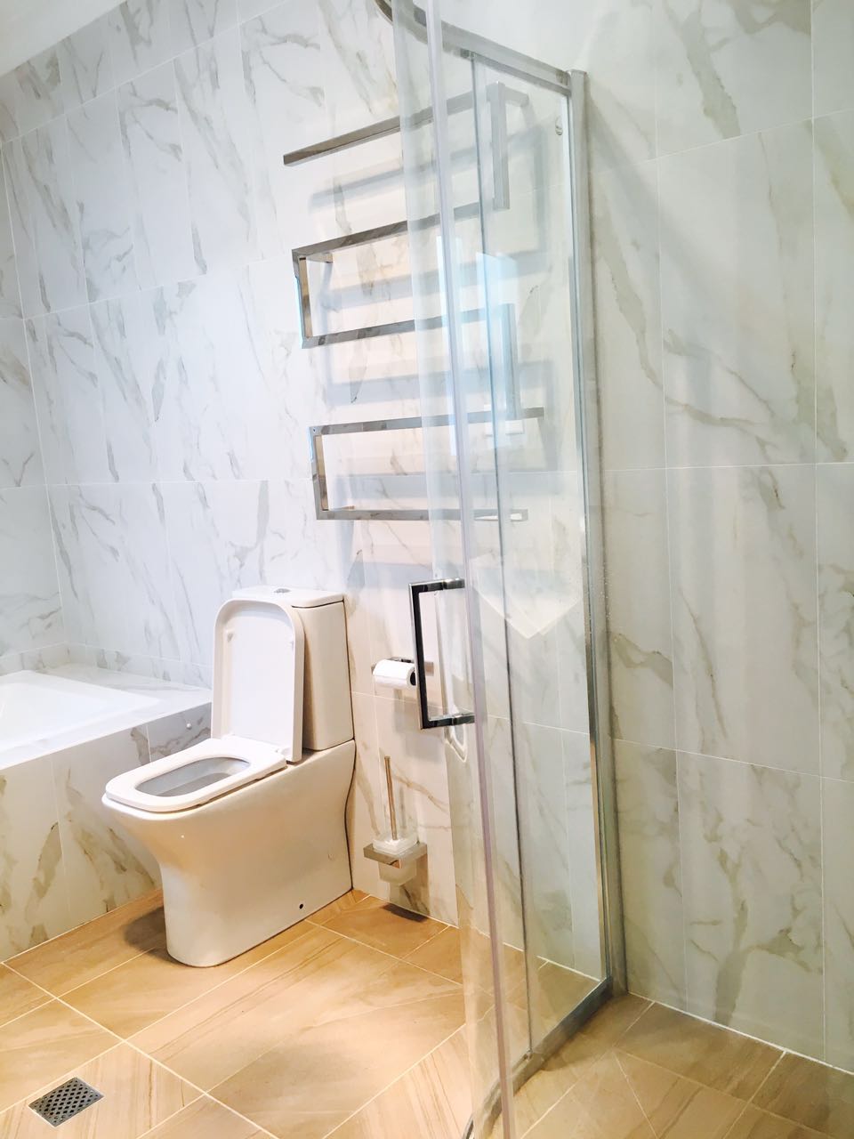 Marble-look tiled bathroom with glass shower screen