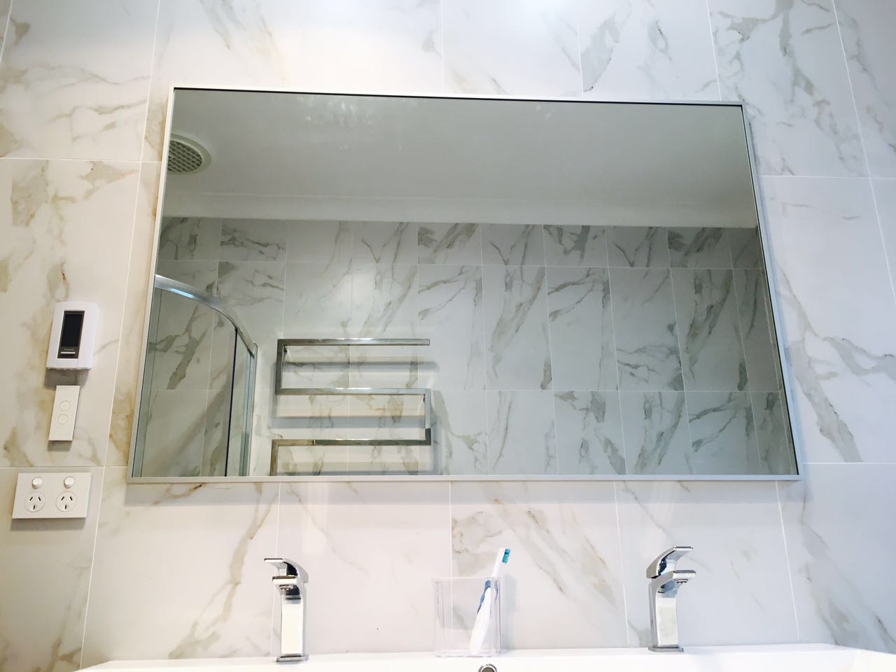 Marble-look bathroom tiling and a wide mirrored cabinet